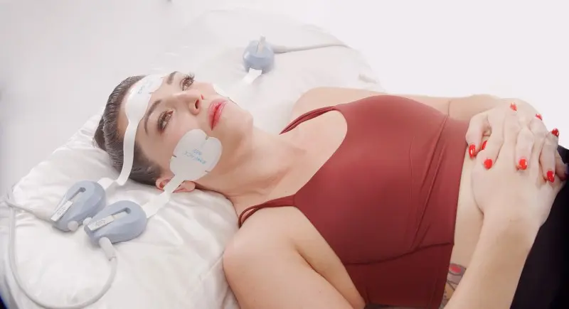 EMFACE facial treatment with applicators on the forehead and cheeks